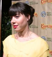 A dark brunette woman wearing a yellow dress smiles.