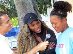 A reporter holding a microphone to Osaka with Williams to the side smiling