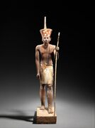 A guardian statue wearing the red crown which reflected the facial features of the reigning king, probably Amenemhat II or Senwosret II, and which functioned as a divine guardian for the imiut; made of cedar wood and plaster ح. 1919–1885 BC