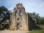 A stone church building with three bells