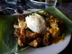 Nasi lemak with chicken curry and prawn on banana leaf