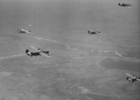 B-24 formation on a mission to Bucharest in 1944. Note the damaged bomber with the smoking engine.