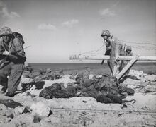 Marines crossing Japanese-laid barbed wire in Betio Island