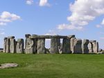 A ring of standing stones some with lintels stands in the middle of a green field