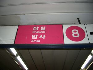 An overhead sign in rose and white with a big number 8 and the words Chamshil and Amsa in hangul and Latin script.