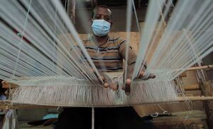 فتى يغزل على نول في مصنع تقليدي للنسيج في أفريقيا.
