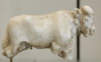 A carved, white statue of a bull missing its legs and with a head showing details of ears, mouth, nose, and eyes