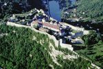 An aerial view of a large building and several other smaller buildings surrounded by a reinforced wall.