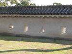 Photo of defensive loopholes in one of the castle walls. Two of the loopholes are rectangle-shaped, one is triangle-shaped, and one is circle-shaped.