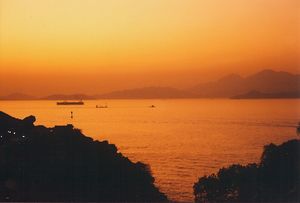 Waters of the harbour and the sky above it are coloured orange by the ash.