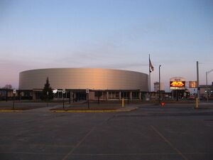 A brightly lit hockey arena, clad in metal panels.