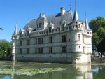 An ornate white castle in the middle of a pond or moat.