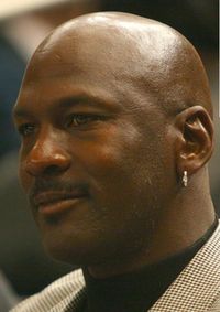 Smiling and imposing bald black man wearing a silver earring and herringbone jacket