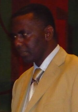 Cropped image of Biram Dah Abeid looking left, wearing a yellow suit, white shirt, and gold tie