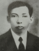 A young man, in a suit with a pale shirt and dark tie