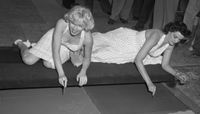 Marilyn Monroe and Jane Russell putting signatures, hand and foot prints in cement at Grauman's Chinese Theater, 1953