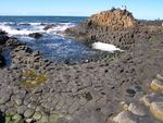 A small cove made up of tall and geometrically distinct rock formations, on which two couples are sitting.