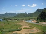 Landscape with river and densely forested hills.