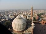 Two Islamic tombs with white domes and several people around